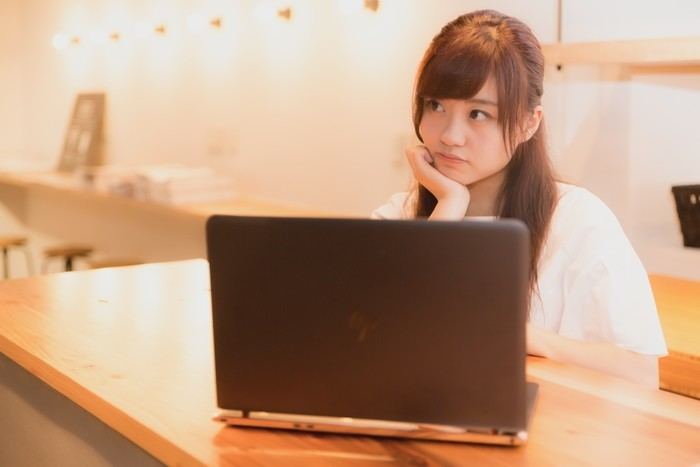 パソコンの前で考えごとをしている女性