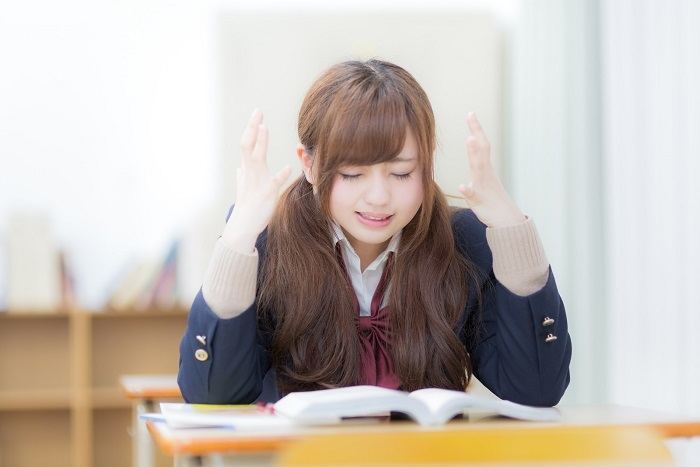 教科書を見て頭を抱えてる女子学生