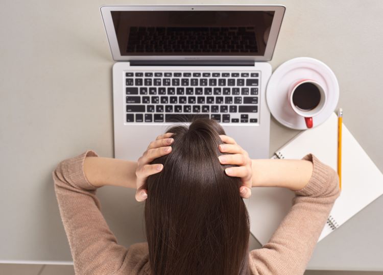 パソコンの前で悩む女性の写真