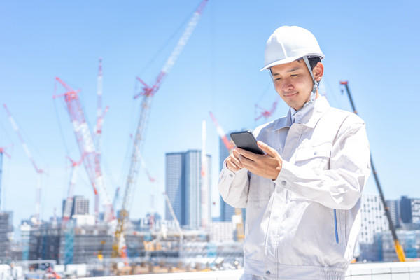 スマートフォンを見る建設現場作業員