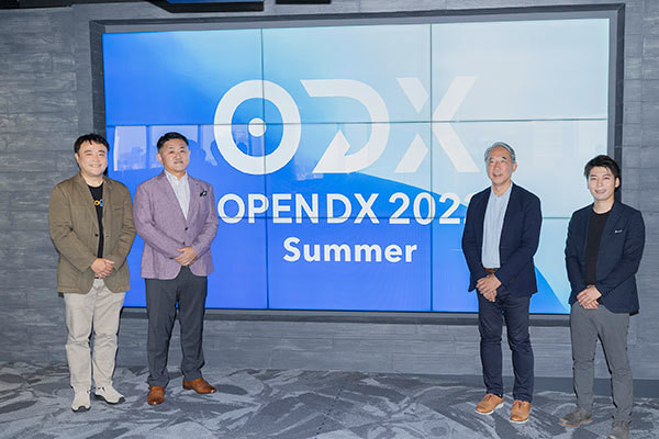 「OPENDX Summer」が投影されたサイネージ前に並ぶ4名