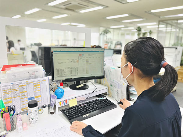 [写真]パソコン作業をする藤松 恵理子氏（業務風景）