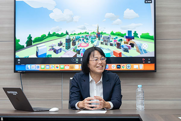 [写真]メタバースをバックに鼎談で発言する戸田氏